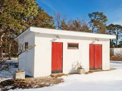 Liten putsad byggnad med röda dörrar